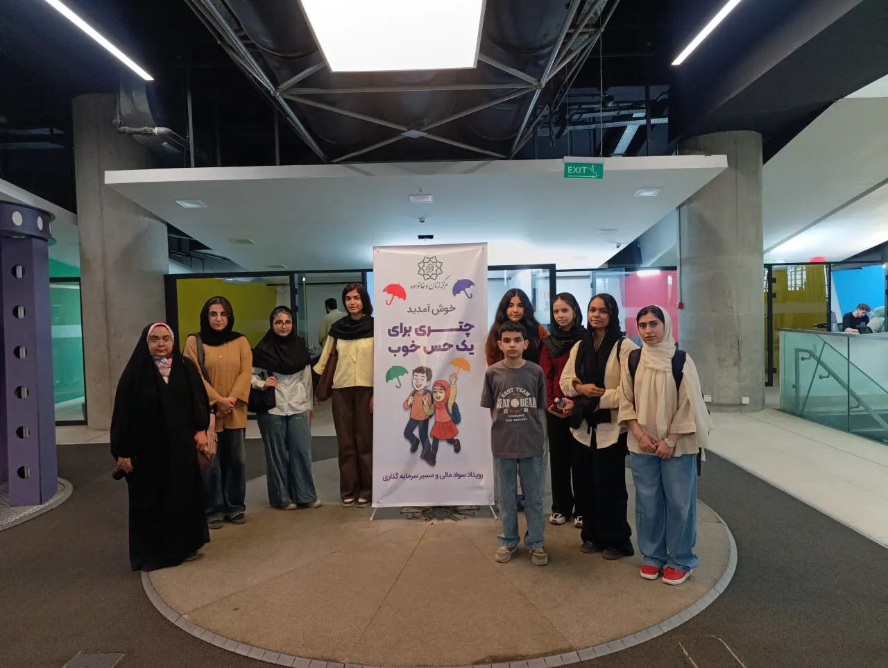 گروه نوجوانان کنار بنر «چتری برای یک حس خوب»